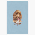 Colored pencil portrait of an apricot labradoodle printed on a french blue fleece blanket, with the name "Cooper" drawn below.