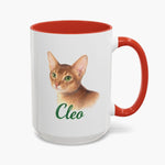 Colored pencil portrait of a ginger Abyssinian cat on a 15 oz mug with a red handle, with the name "Cleo" drawn below.
