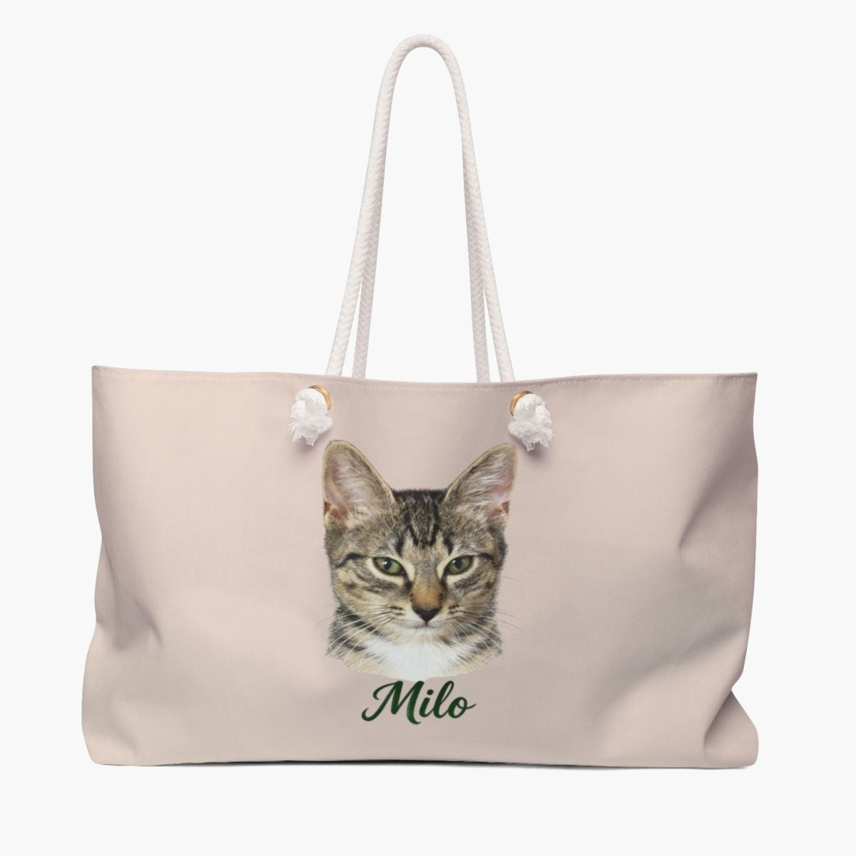 Colored pencil portrait of a tabby cat on a dusty pink weekender bag with white rope handles, with the name "Milo" drawn below.